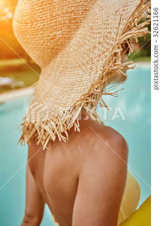 Girl in a sun hat next  the pool 32621166