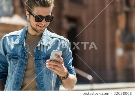 Happy youthful man with beard using gadget outdoor 32628008