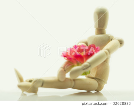 The wooden puppet sitting and hugging pink flowers The wooden puppet sitting and hugging pink flowers 32628883