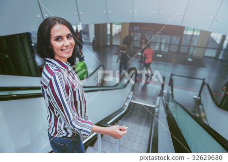 Cheerful young woman is getting down on staircase Cheerful young woman is getting down on staircase 32629680
