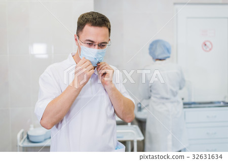 Thoughtful male surgeon wearing surgical mask in 32631634