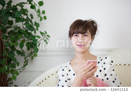 在沙發上使用智能手機的年輕女士 32641318