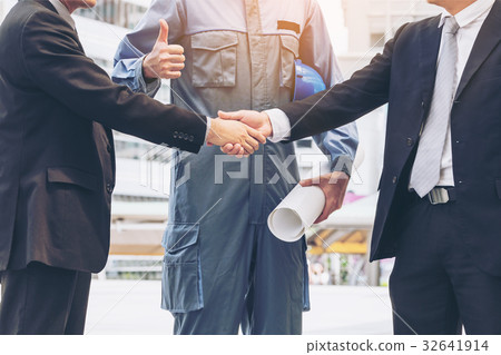 Businessmen handshake with engineer thumbs up Businessmen handshake with engineer thumbs up 32641914