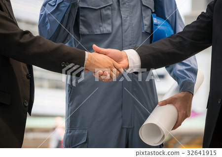 Businessmen handshake with engineer behind Businessmen handshake with engineer behind 32641915