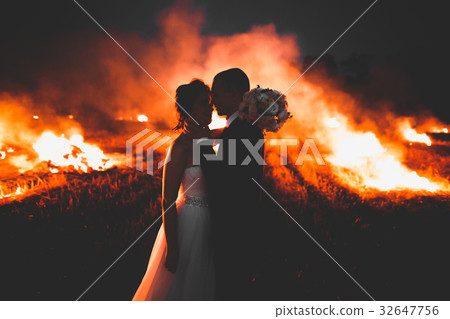 Amazing wedding couple near the fire at night Amazing wedding couple near the fire at night 32647756