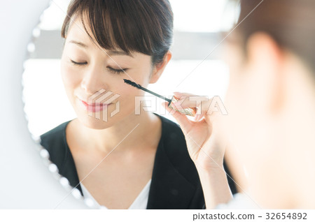 A woman in a suit applying makeup A woman in a suit applying makeup 32654892