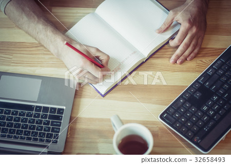 Top view of freelancer man writing in notebook at Top view of freelancer man writing in notebook at 32658493