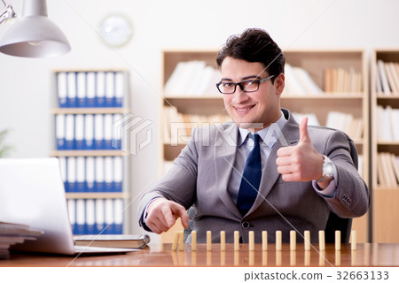 Businessman with dominoes in the office Businessman with dominoes in the office 32663133