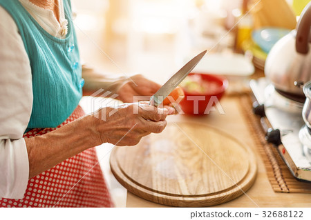 Senior woman hands chopping vegetables on a wooden Senior woman hands chopping vegetables on a wooden 32688122