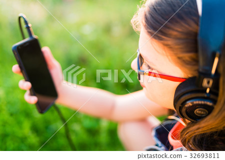 Teen girl listening to music with her headphones outdoor Teen girl listening to music with her headphones outdoor 32693811
