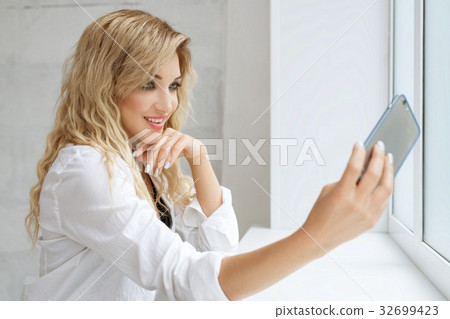 Sexy girl in white shirt making selfie in studio 32699423