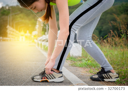Young woman tying her sports shoes on exercising Young woman tying her sports shoes on exercising 32700173