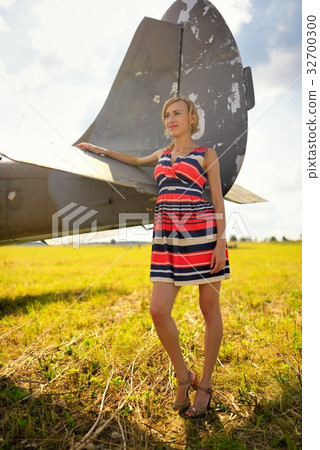 Fashion beautyful woman in dress stays near the old plane 32700300