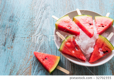 Watermelon slice popsicles on a blue rustic wood Watermelon slice popsicles on a blue rustic wood 32702355