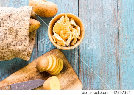 Pile of potatoes lying on wooden boards with a potato bag in the 32702395
