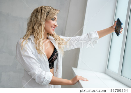 Sexy blonde making selfie near window in studio 32709364