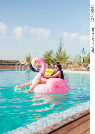 girl sits on inflatable mattress flamingos in pool girl sits on inflatable mattress flamingos in pool 32709846