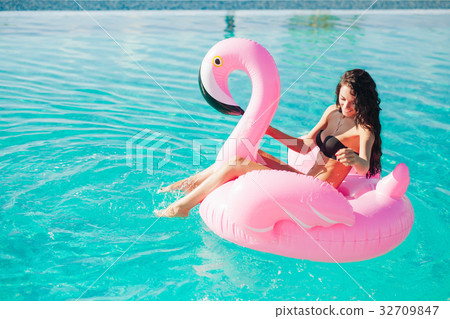 girl sits on inflatable mattress flamingos in pool girl sits on inflatable mattress flamingos in pool 32709847