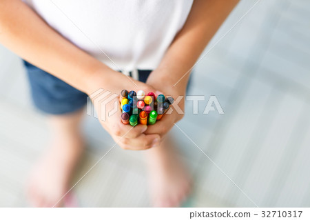 child's hands with lots of colorful wax crayons 32710317