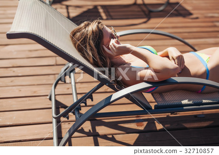 young woman swimsuit laying chaise-longue poolside young woman swimsuit laying chaise-longue poolside 32710857