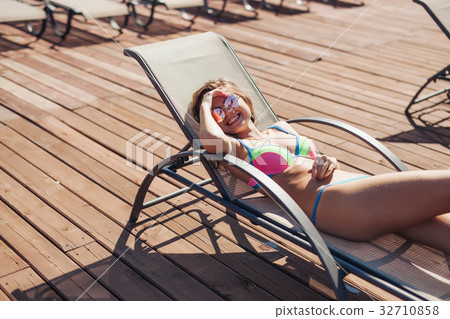 young woman swimsuit laying chaise-longue poolside young woman swimsuit laying chaise-longue poolside 32710858