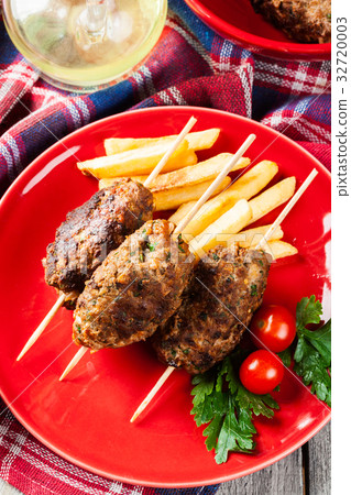Barbecued kofta with fries on a plate 32720003