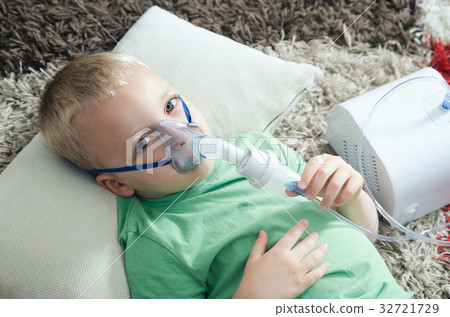 Boy making inhalation with nebulizer at home 32721729
