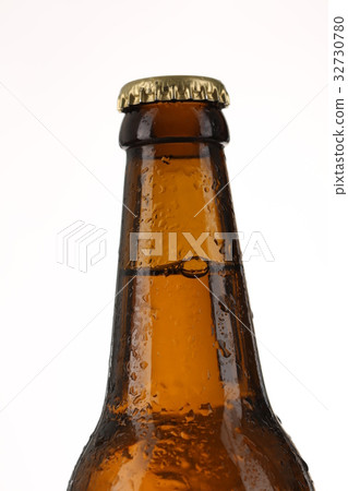 Glass bottle of beer with drops. Close up. White 32730780