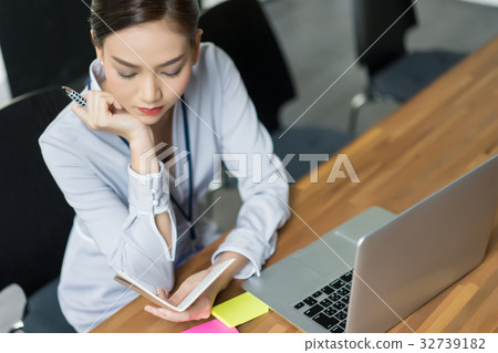 The woman is reading her notebook and thinking The woman is reading her notebook and thinking 32739182