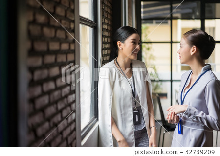 Two business women are standing and talking at the office 32739209
