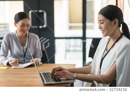 two businesswomen are sitting, working and smiling 32739238