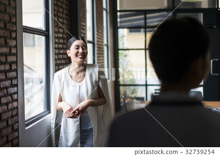 young woman is standing next to the window and smiling at someone young woman is standing next to the window and smiling at someone 32739254