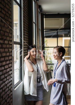 two happy girls are talking together next to the window two happy girls are talking together next to the window 32739255