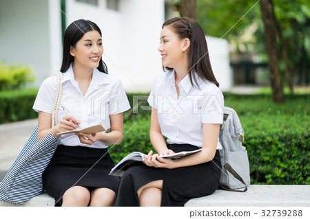 Two college students are sitting, talking together in the campus 32739288