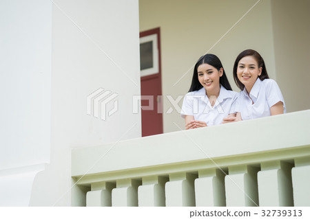 two girls in uniform are standing in a balcony and smiling two girls in uniform are standing in a balcony and smiling 32739313
