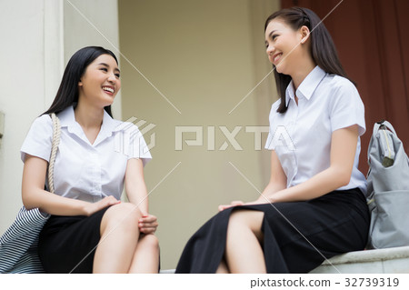 two high school girls are sitting and talking 32739319