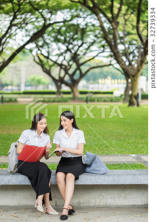 two female students are sitting and discussing on campus 32739334