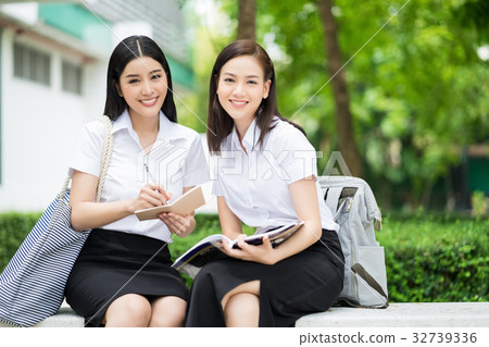 two smiling students are sitting and looking at camera two smiling students are sitting and looking at camera 32739336
