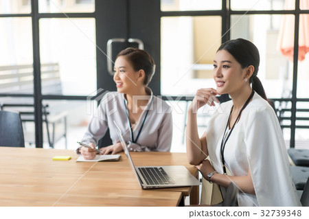 Two happy women are sitting and working in the office Two happy women are sitting and working in the office 32739348