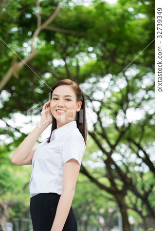 A beautiful student is smiling and standing in the park A beautiful student is smiling and standing in the park 32739349