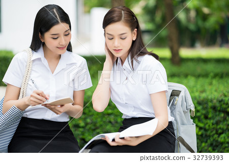 The portrait of two girls sitting outdoors and dicussing together The portrait of two girls sitting outdoors and dicussing together 32739393
