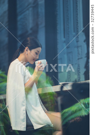 a photo of a woman enjoying a drink in a coffee shop. a photo of a woman enjoying a drink in a coffee shop. 32739445