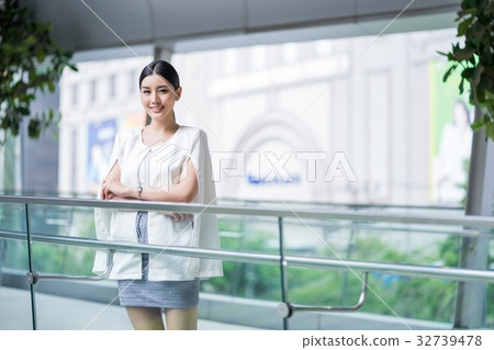 a girl is standing at a glass balcony and smiling. a girl is standing at a glass balcony and smiling. 32739478