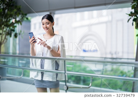 a picture of a girl standing on a balcony and using her phone 32739479