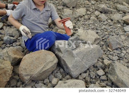 A child breaking a stone in a fossil excavation experience 32748049