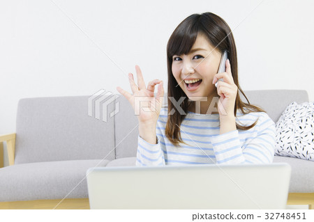 一位年輕的女士用個人電腦打電話 32748451