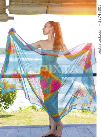 The young woman in a bright scarf pareo stand on a 32748803