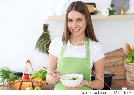 Young happy woman is cooking or eating fresh salad Young happy woman is cooking or eating fresh salad 32751659