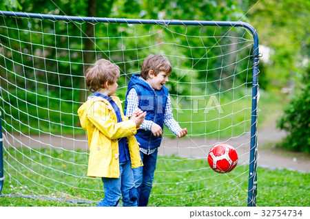 Two active kids boys playing soccer and football Two active kids boys playing soccer and football 32754734