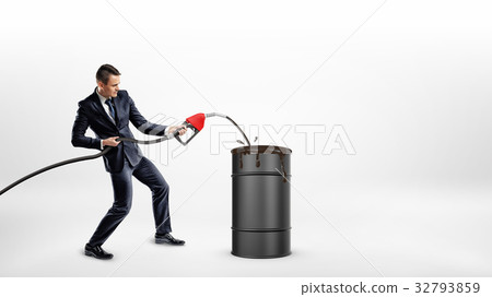 A businessman holds a gas nozzle and overfills a 32793859
